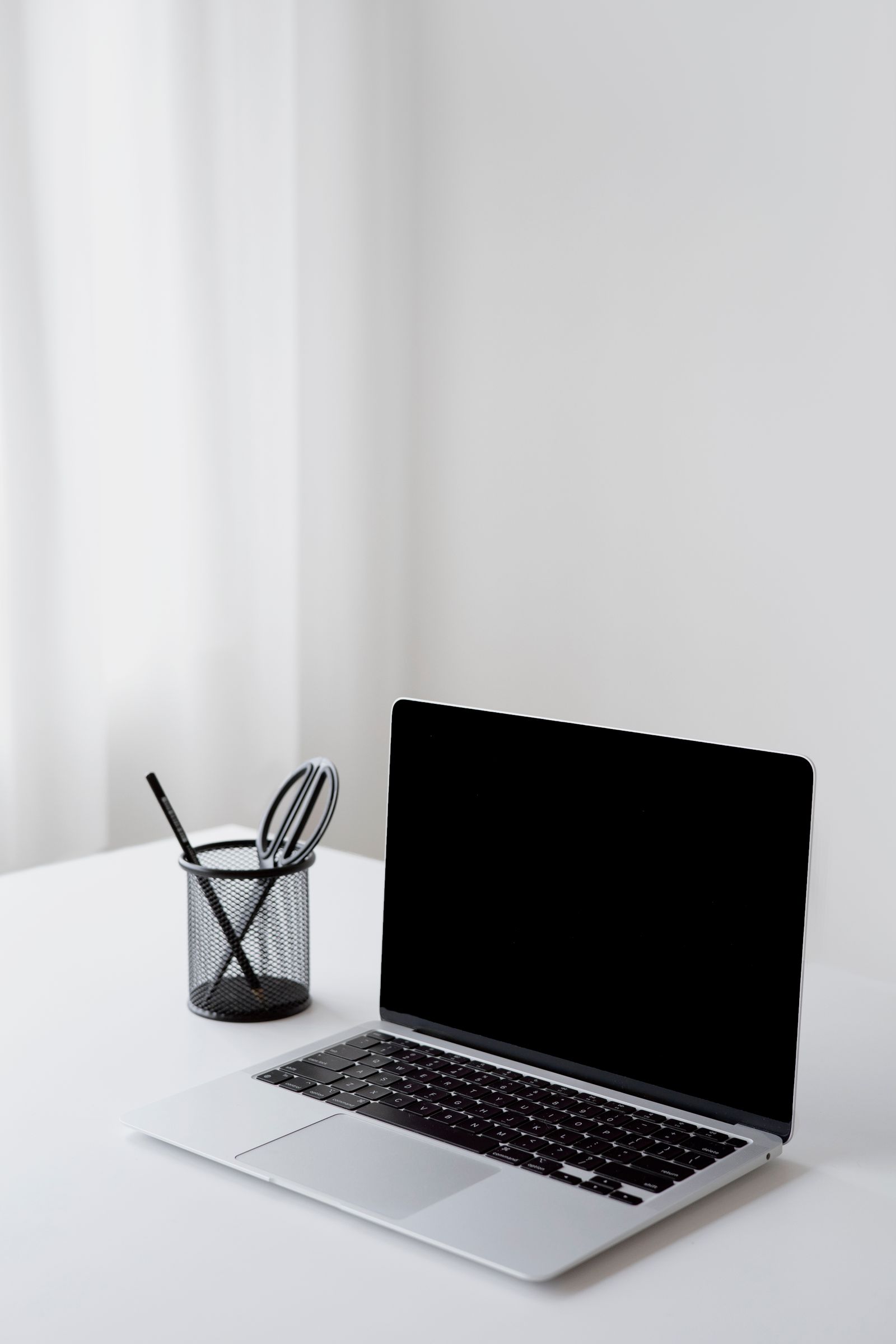 An open laptop and stationery on a clean white desk